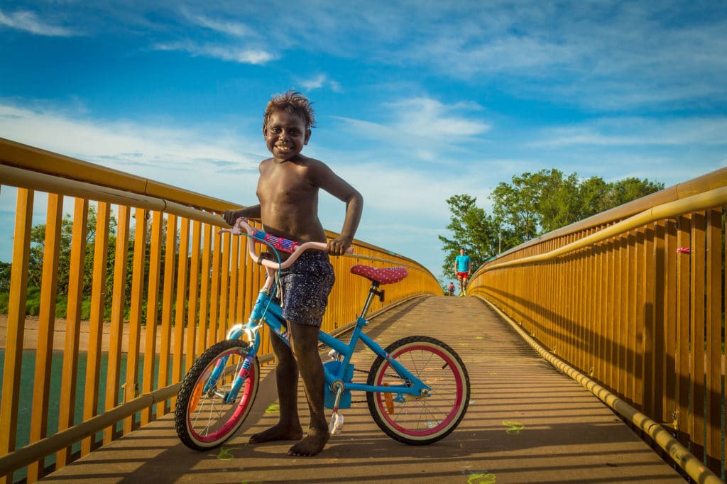 Happy Child On A Bike Going Across A Bridge